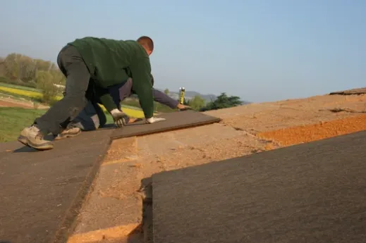 Couvreur qui pose une couverture après isolation sarking